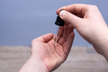 Man dripping beard oil into his palm from a pipetteの写真素材