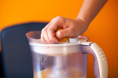 Girl squeezing an orange with an electric citrus juicerの写真素材