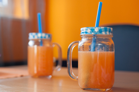 Two jars of fresh citrus juice with cute lids and strawsの写真素材