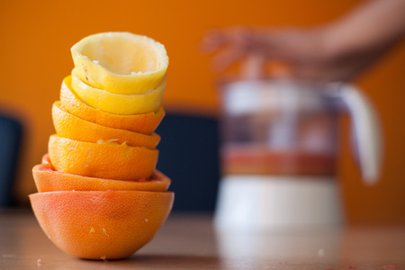 Pile of freshly squeezed citruses with the juicer in use in the backgroundの写真素材