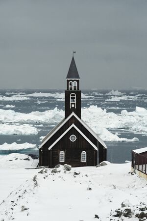 Snow covered Zion church in Ilulissat Greenland with the Disco Bay in the backgroundの写真素材