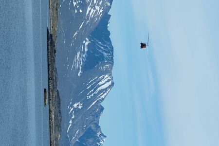 Red helicopter in Fight over Nanortalik Greenland with mountain range in the background