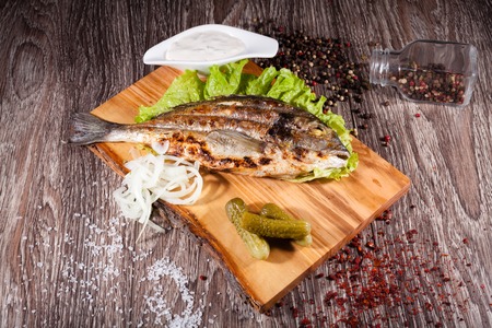 Grilled sea bream on a wooden board and lettuce, tartar sauce wiの写真素材