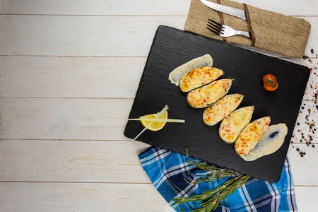 Ready mussels on a stone board, with a wooden background and a linen towel. herbs spices lemonの写真素材