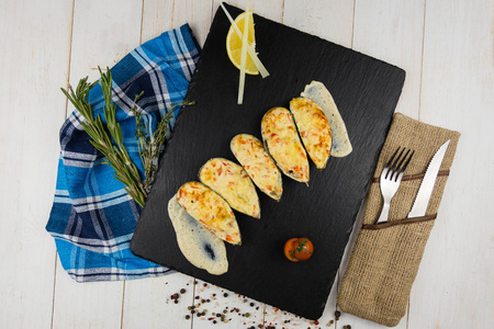 Ready mussels on a stone board, with a wooden background and a linen towel. herbs spices lemonの写真素材