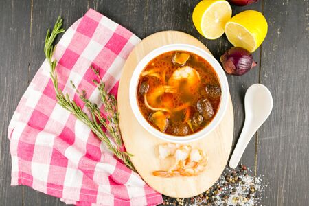 tom yam soup with shrimp on a linen towel on a wooden backgroundの写真素材