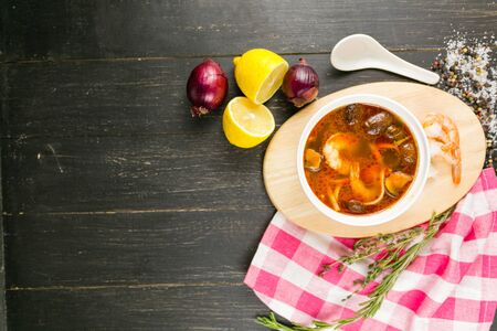 tom yam soup with shrimp on a linen towel on a wooden backgroundの写真素材