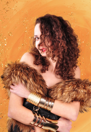 young girl with curly hair in a fur coat on an abstract backgroundの写真素材