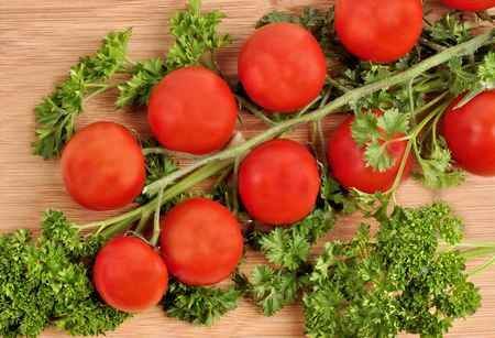 Small cherry tomatoes with parsley on a wooden backgroundの写真素材