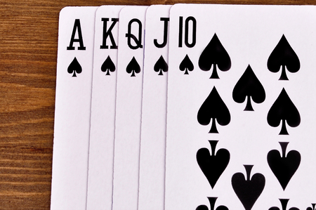 Combination of royal flush of playing cards on a wooden background