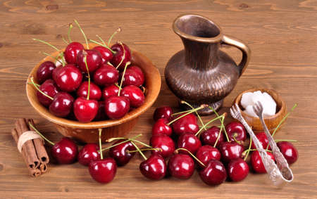 Cherries in a wooden bowl with a bowl for juice on a wooden backgroundの写真素材