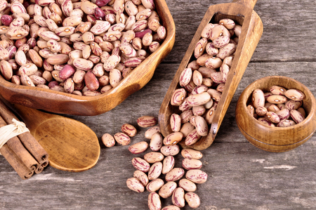 Colored beans in a wooden bowl on an old wooden backgroundの写真素材