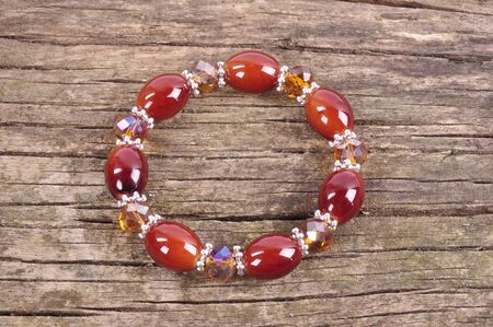 Bracelet burgundy color with crystals on the background of an old wooden tableの写真素材