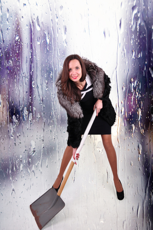 extravagant woman in a half hem with a shovel for snow removal on an abstract background.の写真素材
