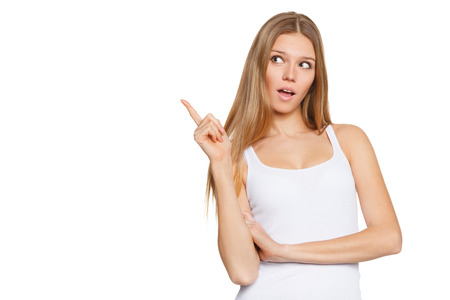 Beautiful surprised woman in excitement pointing to the side. Isolated over white backgroundの写真素材