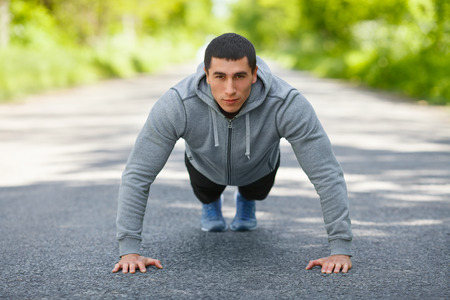 Fitness man exercising push ups, outdoor. Muscular male cross-training on city parkの写真素材