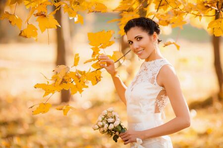 Happy bride in autumn park. Smiling girl in a white dress, outdoorsの写真素材