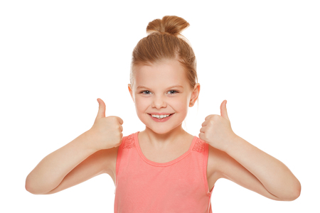 Happy joyful little girl smiling showing thumbs up, isolated on white backgroundの写真素材