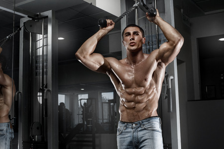 Sexy muscular man working out in gym, shaped abdominal. Strong male naked torso abs