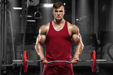Muscular man working out in gym doing exercises with barbell, strong maleの写真素材