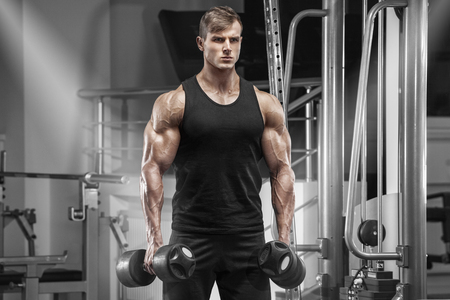 Muscular man working out in gym doing exercises, handsome strong maleの写真素材