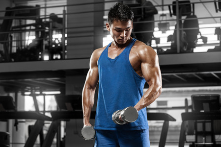 Muscular man working out in gym doing exercises for biceps, strong maleの写真素材