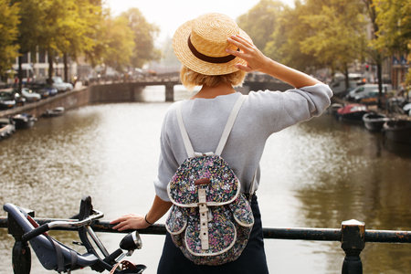 Happy traveler girl enjoying Amsterdam city. Tourist woman looking to the Amsterdam canal, Netherlands, Europeの写真素材