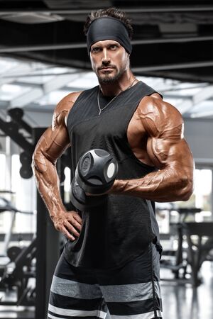 Muscular man workout in gym. Strong male doing exercise for bicepsの写真素材