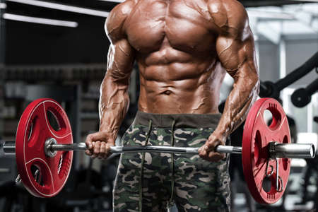 Muscular man in gym doing exercises for biceps, working out. Strong male naked torso absの写真素材