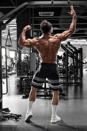 Muscular man in gym showing back muscles rear view. Strong male  torsoの写真素材