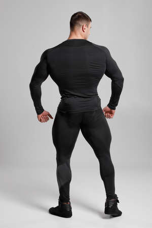 Muscular man in black compression sportswear rear view on gray backgroundの写真素材