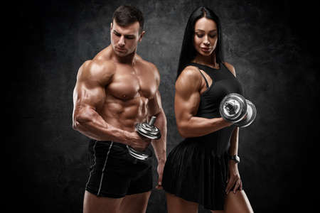Sporty couple working out on wall background. Muscular man and womanの写真素材