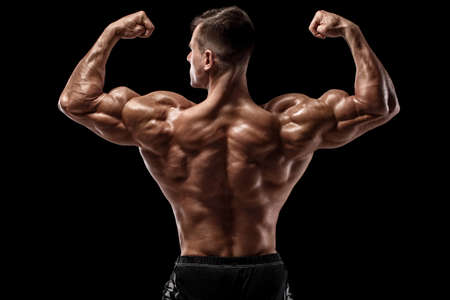 Muscular man showing back muscles, isolated on black background. Strong male rear viewの写真素材