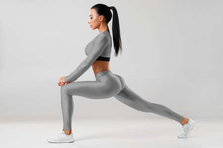 Fitness woman doing lunges exercises for leg muscle training. Active girl doing front forward one leg step lunge exerciseの写真素材
