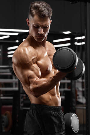 Muscular man working out in gym doing exercise for biceps, strong male bodybuilderの写真素材