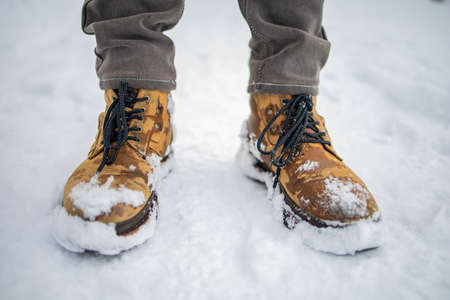 Male Feet In Yellow Boots Walking In Winter Snowの写真素材
