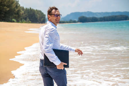 Businessman working with computer on beach, nice outdoor office.の写真素材