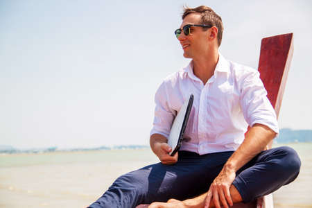 Businessman working with computer on beach, nice outdoor office.