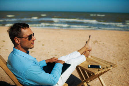 Young man with Laptop computer during tropical beach vacationの写真素材