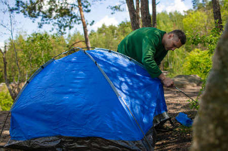 A Man Puts Up A Tent On The Site Of A Future Camp In The Forest