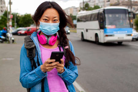 Chinese Woman Waiting For Bus At Bus Stop In City Street And Wearing Face Mask