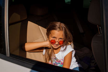 Happy Little Girl Looking Out The Window Of A Car In Outdoor Area
