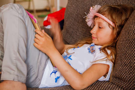 Girl using digital tablet on sofa at home.の写真素材