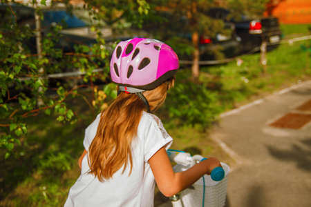 Cute little girl kid in a helmet riding a bike in the park. Beautiful baby with smile.の写真素材