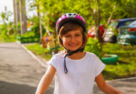 Cute little girl kid in a helmet riding a bike in the park. Beautiful baby with smile.の写真素材
