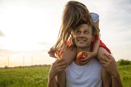 Young father holding little daughter and standing on green field.の写真素材