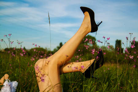 A beautiful young woman lifting her legs up for green grass background.の写真素材