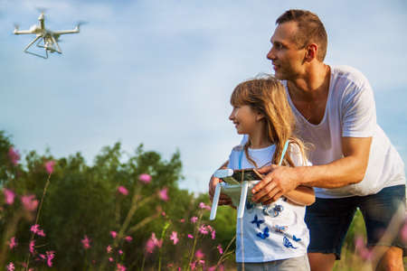 outdoor recreation Leisure for family. Birthday gift. A man and little girl launch a radio-controlled aircraft or a drone or a helicopter into the sky.の写真素材