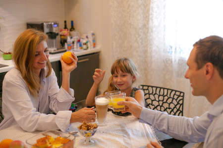 Family have breakfast at the table and drink orange juice in the morning.の写真素材