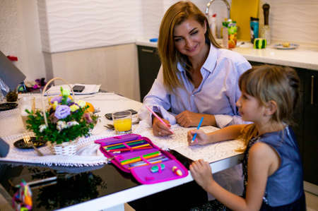 Mom and daughter at the table draw. mother learns with the child at home.